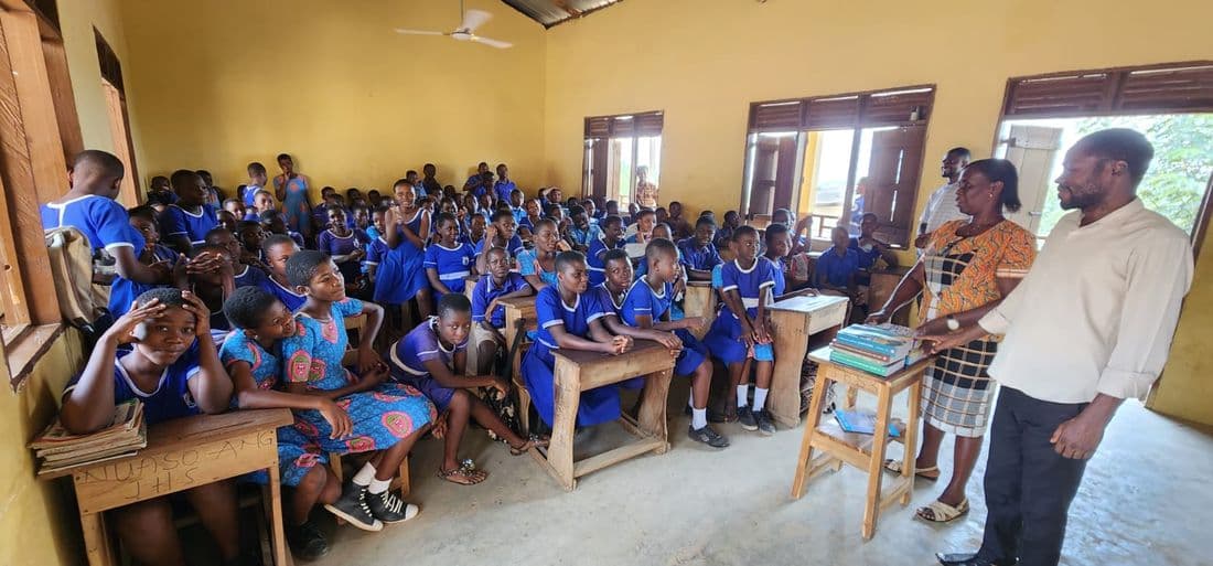 A classroom of school children seated at wooden desks as staff address them during a foundation visit